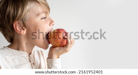 Close up caucasian child biting red apple over white background. Copy space. Side view. Extra wide banner, copy space. Royalty-Free Stock Photo #2161952401