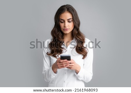 Serious business woman looking at the phone screen, reading message on smartphone, typing text on smart mobile phone. Female freelancer chatting by mobile phone. Royalty-Free Stock Photo #2161968093