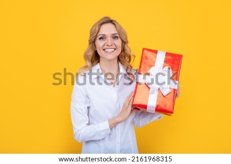 positive woman hold big present box on yellow background
