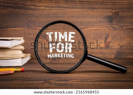 Time For Marketing concept. Magnifying glass on a dark wooden background.