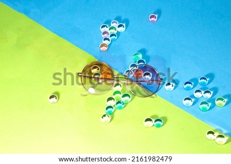 sunglasses on a green-blue background with 3d transparent colorful balls, creative summer concept