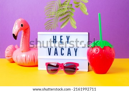 Inflatable flamingo, pink sunglasses, strawberry mug and lightbox with quote Hey Vacay on bright background. Retro vibe or 80s, nostalgic style, retro aesthetic still life. Summer vacation vibes.