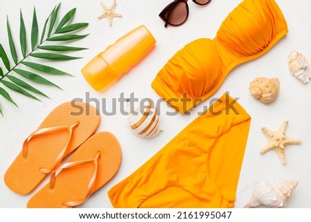 Woman swimwear and beach accessories flat lay top view on colored background Summer travel concept. bikini swimsuit, straw hat and seasheels. Copy space Top view.