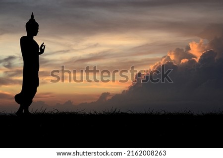 Silhouette with black buddha on sunset background.