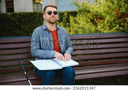 Blinded man reading by touching braille book.