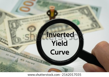 Inverted Yield Curve.Magnifying glass showing the words.Background of banknotes and coins.basic concepts of finance.Business theme.Financial terms. Royalty-Free Stock Photo #2162017035
