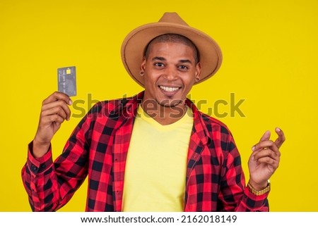 afro brazilian man with credit card in stusio on yellow background.farmer taking a loan in a bank for small business in agriculture