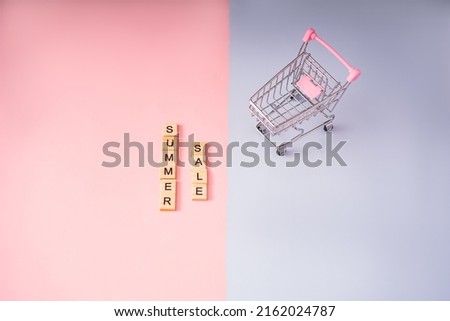 summer sale letters with an empty shopping basket on a pink and blue background. the concept of summer shopping