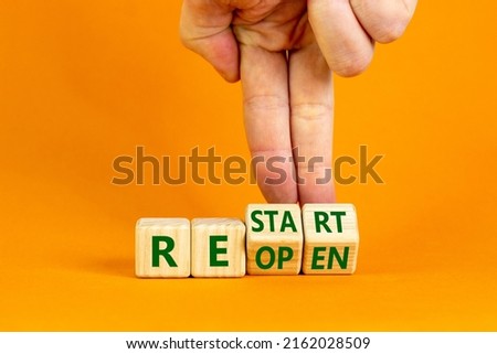 Reopen and restart symbol. Businessman hand turns cubes and changes the word 'reopen' to 'restart'. Beautiful orange background. Business and reopen - restart concept. Copy space. Royalty-Free Stock Photo #2162028509