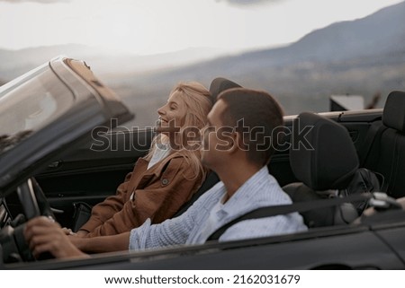 Cheerful young couple man and woman in cabriolet car holding hands feeling happy. Close up, vacation Royalty-Free Stock Photo #2162031679