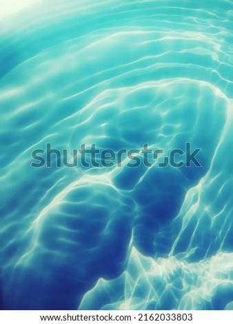 Closeup​ blur​ abstract​ of​ surface​ blue​ water. Abstract​ of​ surface​ blue​ water​ reflected​ with​ sunlight​ for​ background.Top​ view​ of blue​ water.​ Water​ splashed​ use​ for​ graphic​ design