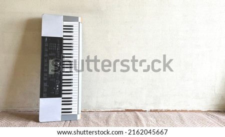 Old electronic keyboard leaning against the wall