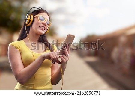 Smiling young woman listening to the podcast e-book music song singer rock band in headphones earphones