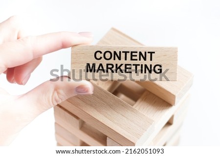 Content marketing text on a wooden bar in the hands of a person, a business concept