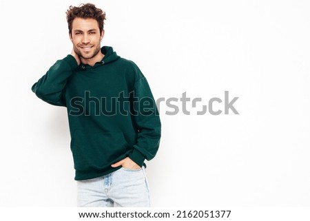 Handsome smiling hipster  model.Sexy unshaven man dressed in summer stylish green hoodie clothes. Fashion male with curly hairstyle posing in studio. Isolated on white Royalty-Free Stock Photo #2162051377