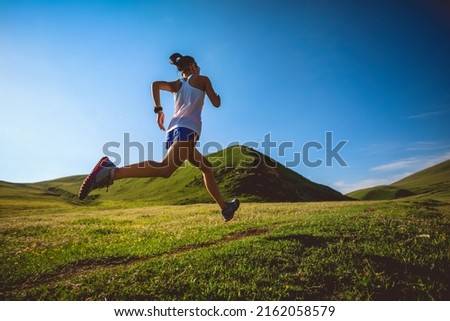 Young fitness woman trail runner running on high altitude grassland Royalty-Free Stock Photo #2162058579