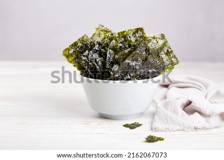 Crispy nori seaweed on bowl on grey background. Traditional Japanese dry seaweed sheets. Healthy snack.  Royalty-Free Stock Photo #2162067073