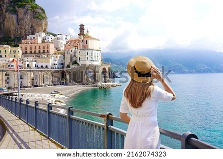 Tourism on Amalfi Coast. Back view of beautiful fashion girl enjoying view of Atrani village on Amalfi Coast, Italy. Summer vacation in Europe. Royalty-Free Stock Photo #2162074323