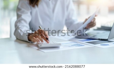 Close-up of businesswoman hands using a calculator to check company finances and earnings and budget. Business woman calculating monthly expenses, managing budget,  papers, loan documents, invoices. Royalty-Free Stock Photo #2162088077