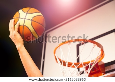 Basketball player putting basketball ball into the hoop in air Royalty-Free Stock Photo #2162088953