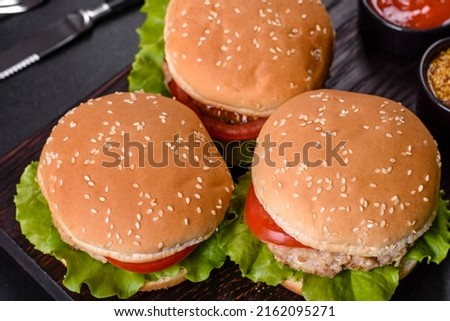 Three hamburger with beef meat burger and fresh vegetables on dark background. Tasty food