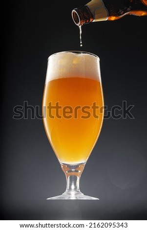 Beer pouring into glass on black background