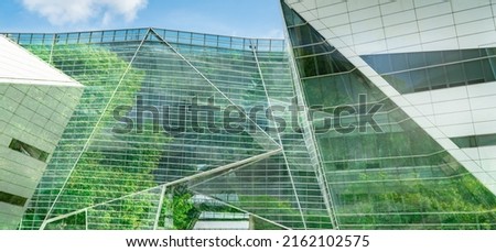 Eco-friendly building in the modern city. Sustainable glass office building with tree for reducing heat and carbon dioxide. Office building with green environment. Corporate building reduce CO2. Royalty-Free Stock Photo #2162102575