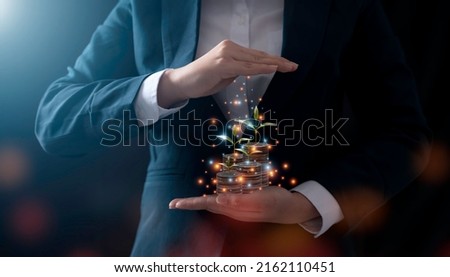 A businessman holding a coin with a tree that grows and a tree that grows on a pile of money. The idea of maximizing the profit from the business investment. Royalty-Free Stock Photo #2162110451
