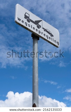 Dutch road sign with icons and text 'Wegsleepregeling' (towing away regulation) on a zinc pole. No parking. Blue sky with clouds. Black text on white Royalty-Free Stock Photo #2162135033
