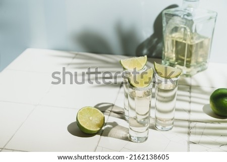 Mexican Gold Tequila with lime and salt on white background with shadows and copyspace. Royalty-Free Stock Photo #2162138605