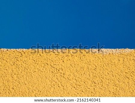 Ukrainian flag as a yellow plaster on a wall and blue sky