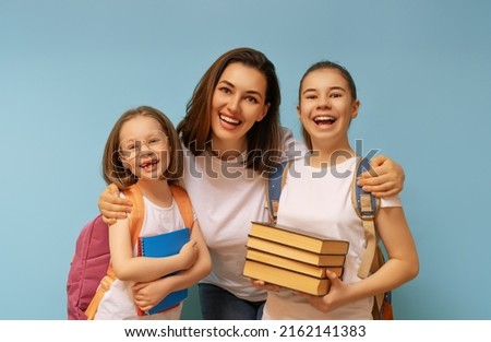 Two schoolers children and their mother teacher on light blue background. Happy time back to school.