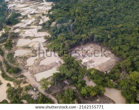 Aerial view of Amazon Rainforest deforestation, illegal gold mine and PC tractor, mercury contaminated river water from mining, forest trees and dirt road used by loggers in logging activity. Brazil Royalty-Free Stock Photo #2162155771