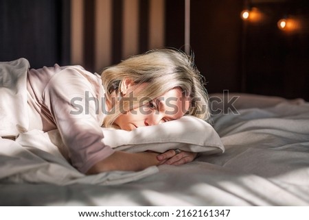 Tired middle aged woman lying in bed can't sleep late at morning with insomnia. Adult lady sick or sad depressed sleeping at home.
 Royalty-Free Stock Photo #2162161347