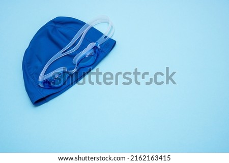 swimming cap and goggles on a blue background with copy space. Royalty-Free Stock Photo #2162163415
