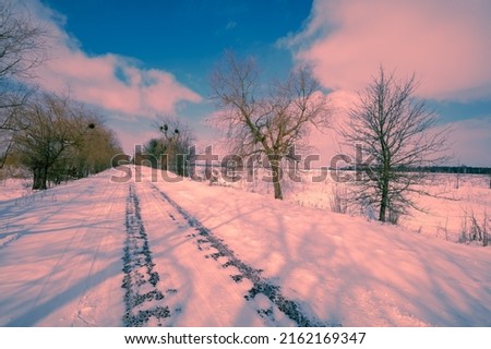Country snowy road in winter during sunset