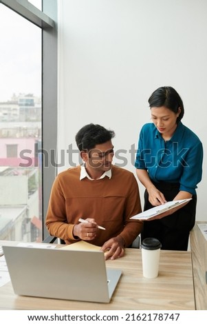 Young businesswoman asking colleague to sign documant on clipboard