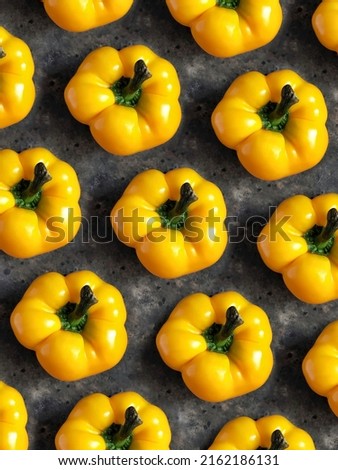 Pattern of yellow sweet bell pepper on black concrete background. Creative flatlay with spring vegetables.
