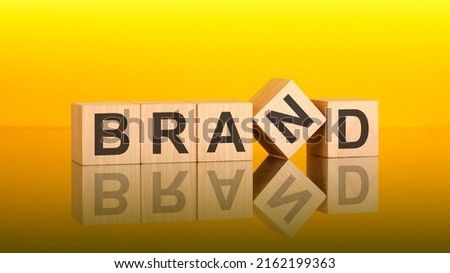brand word written on wood block. yellow background. business concept. inscription on the cubes is reflected from the surface of the table. a color gradient is used