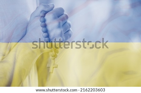 Sad man with Ukraine flag  double exposition at background praying. Concept of standing with Ukrainian