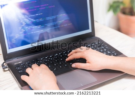 Young woman programmer writing code on pc. Female hands coding and programming on laptop. Web content development software.