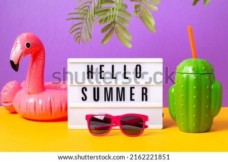 Inflatable flamingo, pink sunglasses, cactus mug and lightbox with quote Hello Summer on bright background. Retro vibe or 80s, nostalgic style, retro aesthetic still life. Summer vacation vibes.