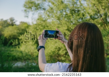 young woman takes pictures of the landscape on the camera phone. selective focus
