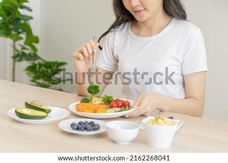 Dieting, diet asian young woman, girl eating, holding fork at broccoli, diet plan nutrition with fresh vegetables salad, enjoy meal on table at home. Nutritionist of healthy, nutrition of weight loss. Royalty-Free Stock Photo #2162268041