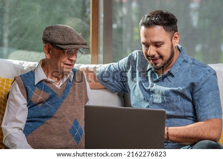 Happy adult senior father with his adult son. Young man enjoys teaching his older father how to use a laptop. How to use technology. Royalty-Free Stock Photo #2162276823