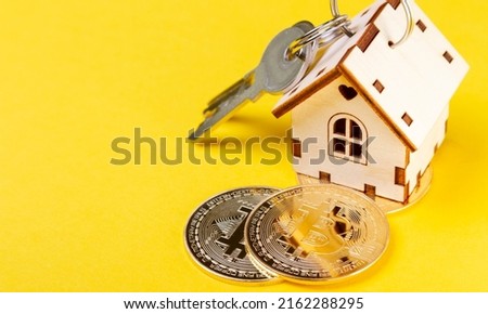 Buying real estate for cryptocurrency. Housing and bitcoins. Coins and house keys. Small wooden house and bitcoin coin.
