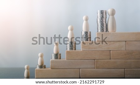 Wooden dolls and stacks of coins are placed on wooden blocks. saves annual growth Compound interest grows through savings, investments, and financial ideas. Royalty-Free Stock Photo #2162291729