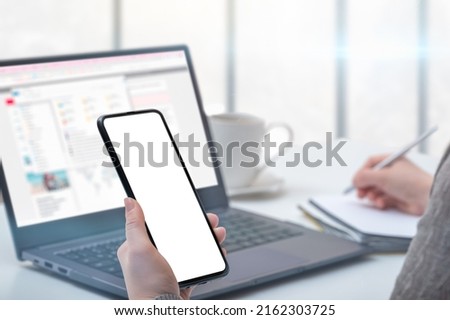 Mockup cellphone. Woman hand holding phone with blank screen in modern office. businesswoman using smartphone with blank screen at workplace desk.