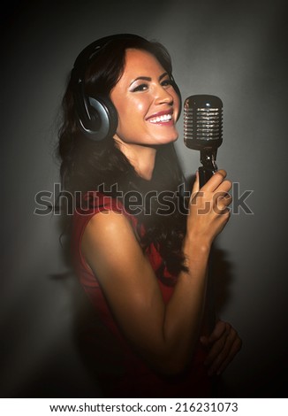 Attractive brunette woman recording a song in music studio.