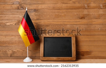 Flag of Germany and board on table against wooden background